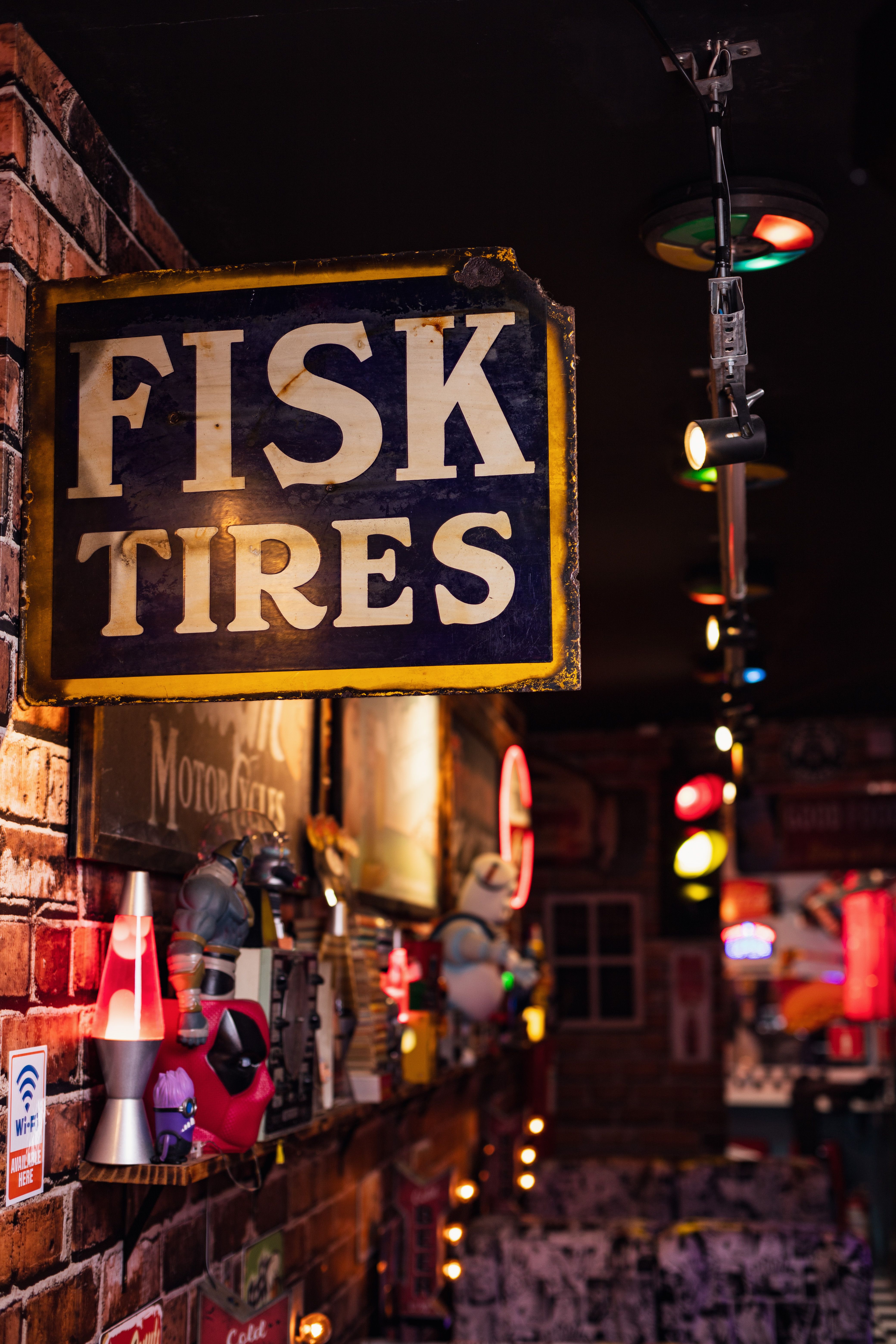 Vintage interior with Fisk Tires sign and colorful collectibles on a brick wall.