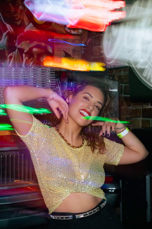 Free Fashionable woman posing with a lively neon backdrop, capturing vibrant nightlife energy. Stock Photo