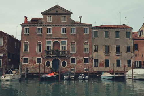 Free Timeless Venetian building facade along a canal with boats in Venice, Italy. Stock Photo