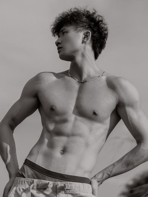 Free Stylish black and white portrait of a shirtless male model with curly hair posing outdoors. Stock Photo