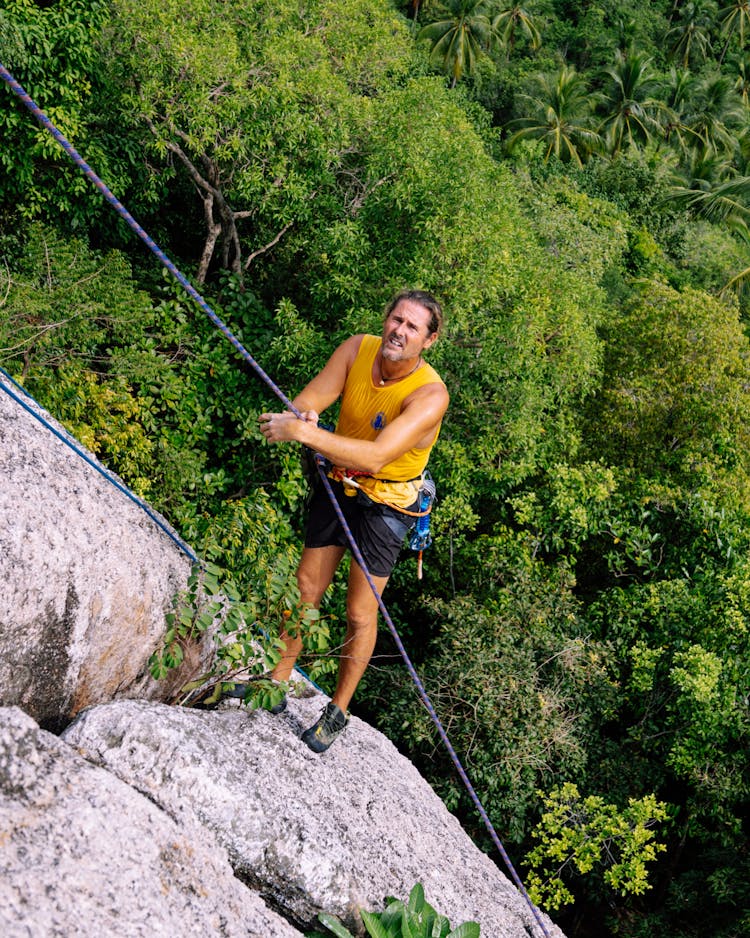 Man Climbing A Rocky Mountain On A Rope 