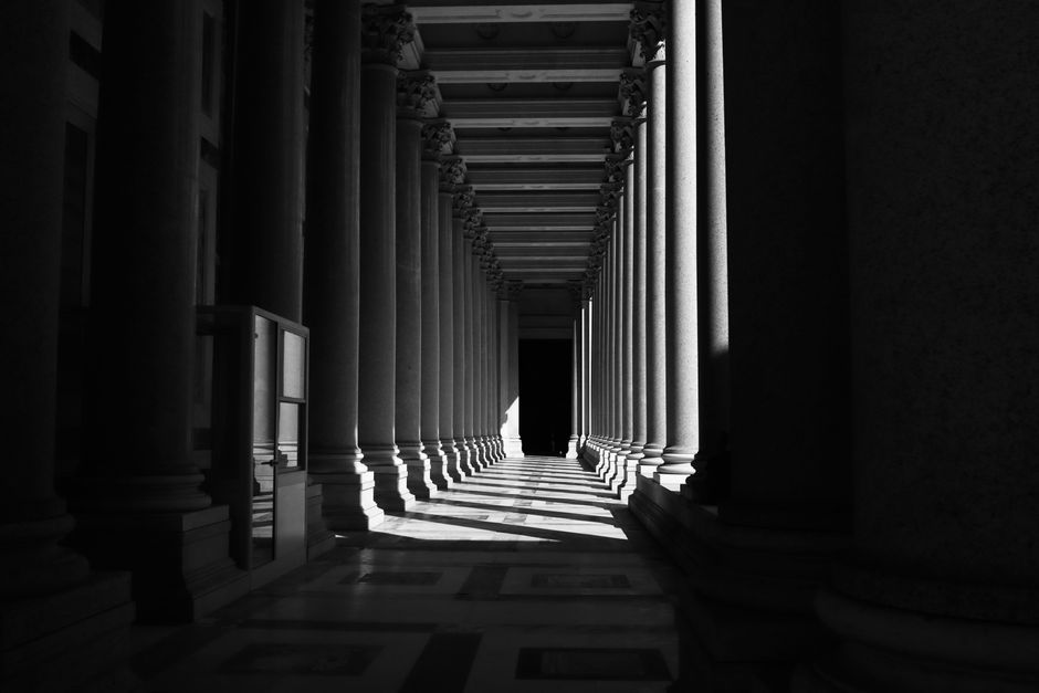 Sunlit colonnade in Rome creates a dramatic play of light and shadow.
