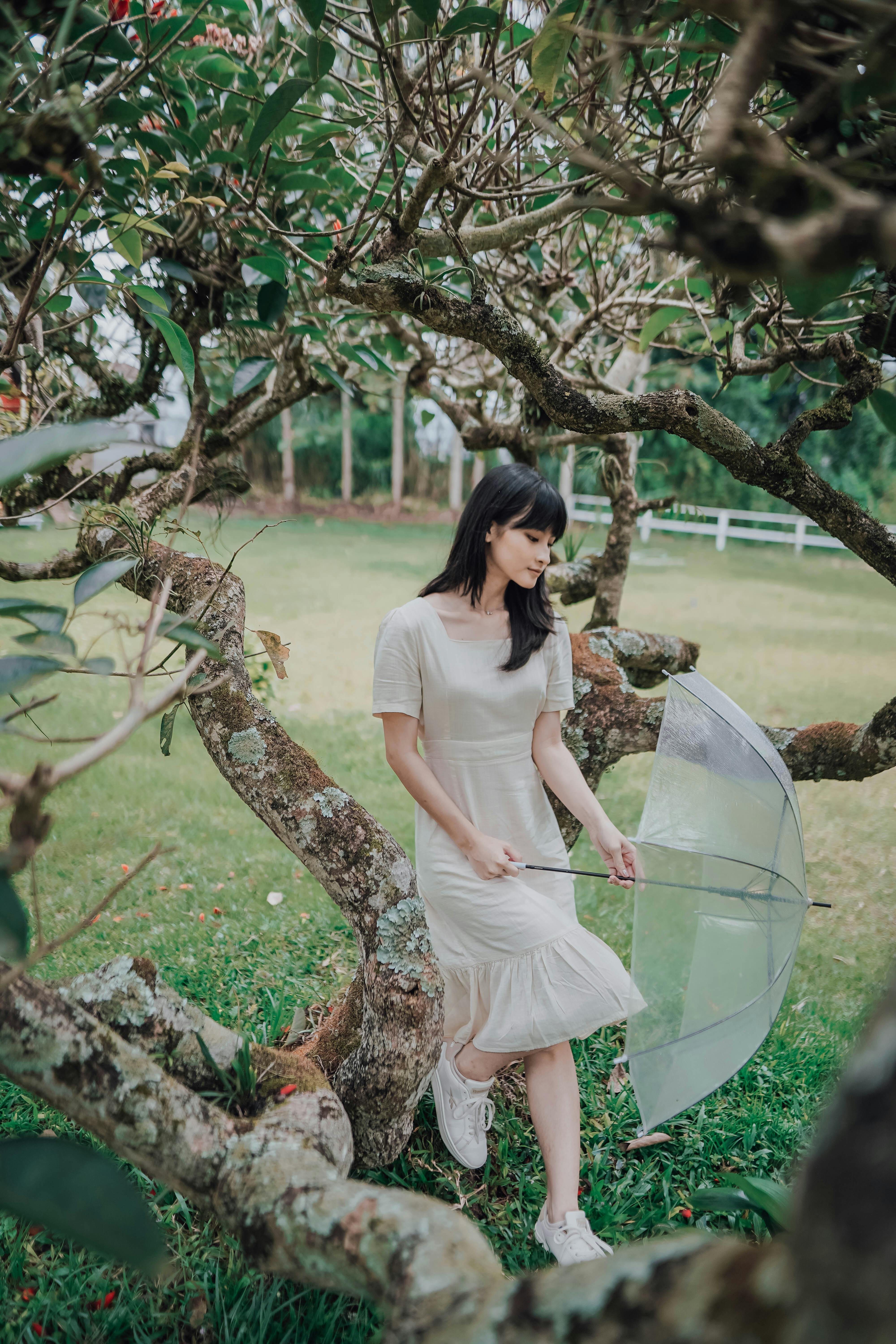 Young woman in a garden in Indonesia holding an umbrella surrounded by lush greenery.
