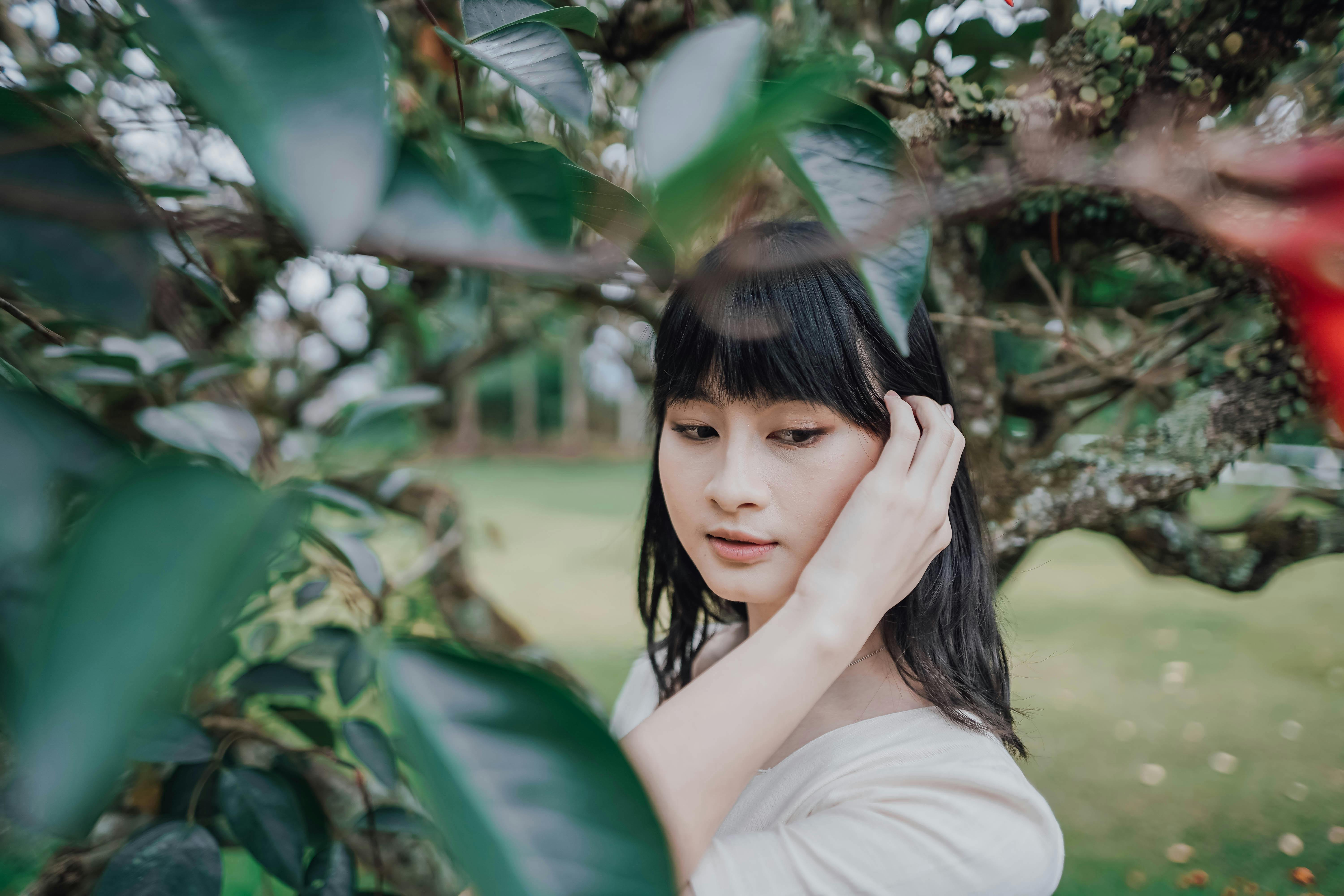 Young Woman Posing Outside between Tree Leaves · Free Stock Photo