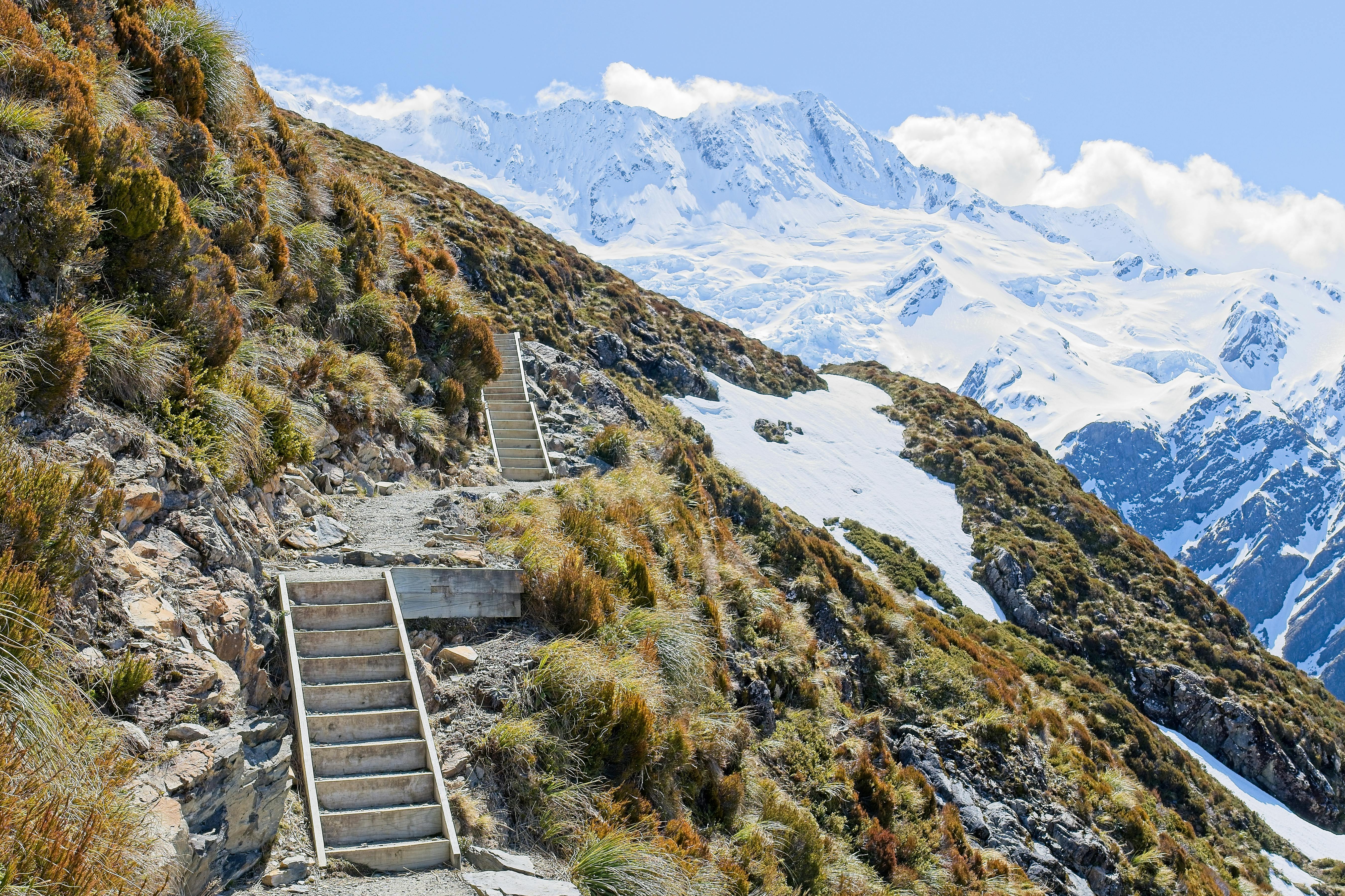 Stunning view of snow-capped Aoraki/Mount Cook with rugged mountain trail in Canterbury, New Zealand.