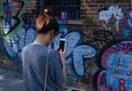 一名年轻女子在城市环境中用智能手机拍摄充满活力的涂鸦