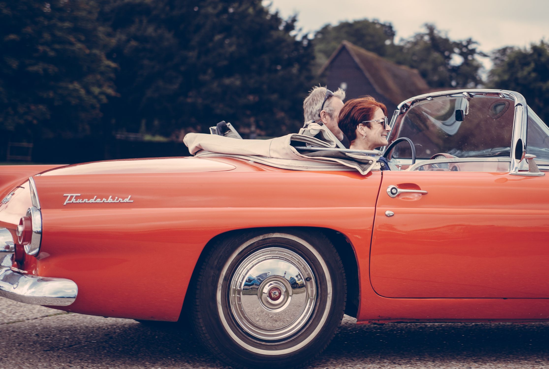 Couple Riding Red Ford Thunderbird during Daytime · Free Stock Photo