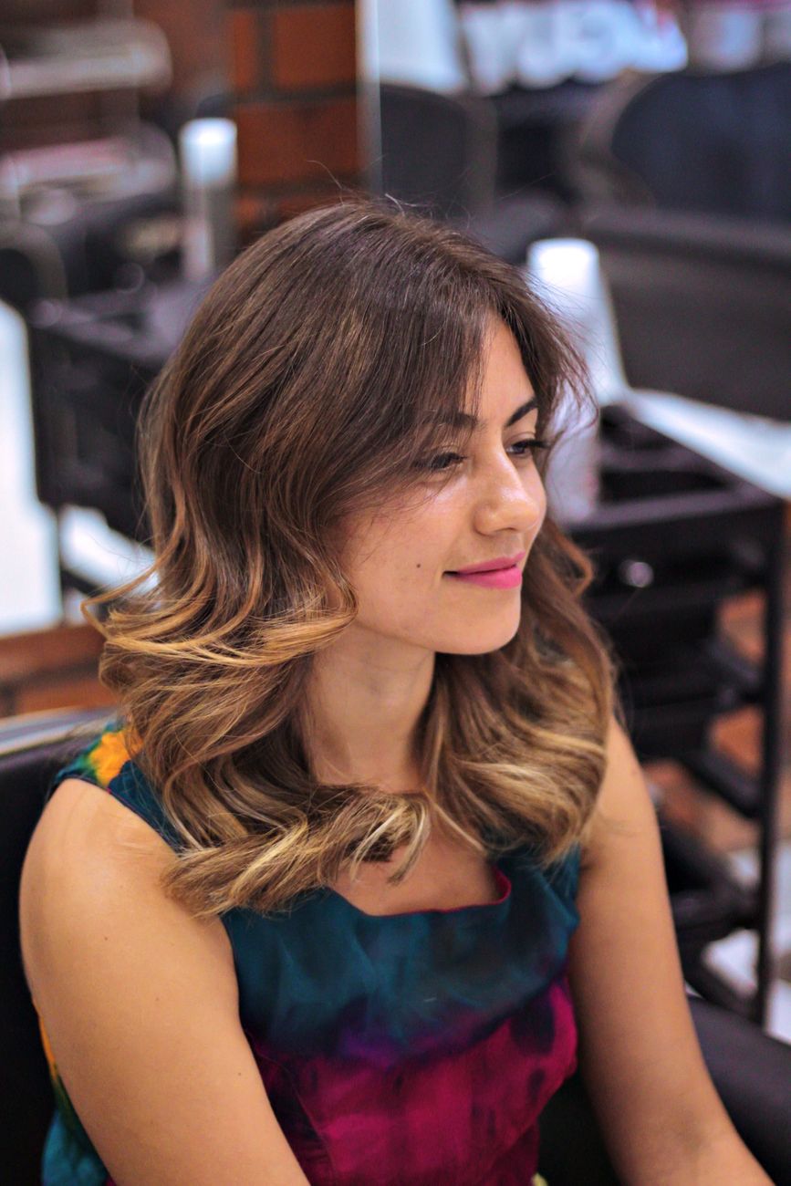 Portrait of a young woman with curly ombre hair, sitting in a salon, exuding glamour and confidence