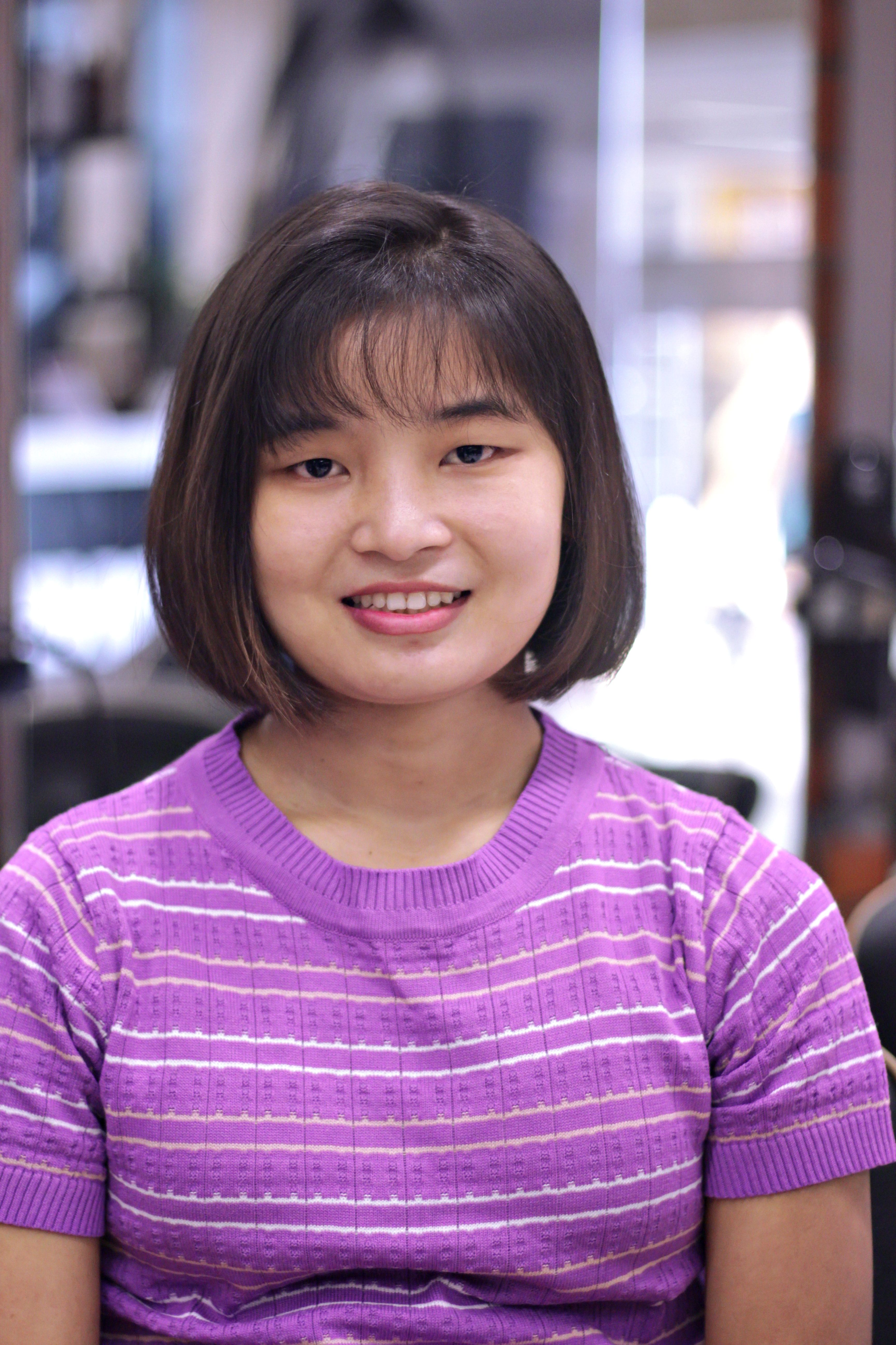 Portrait of a smiling woman with short hair in a purple striped t-shirt, indoors.