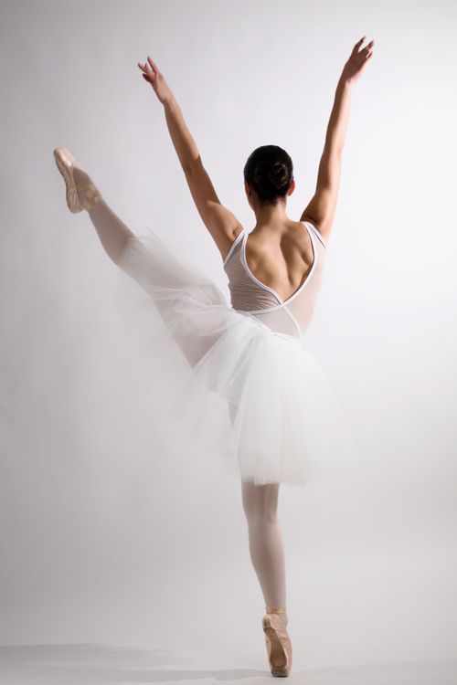 Free Graceful ballerina posing in a classic ballet position in a studio setting. Stock Photo