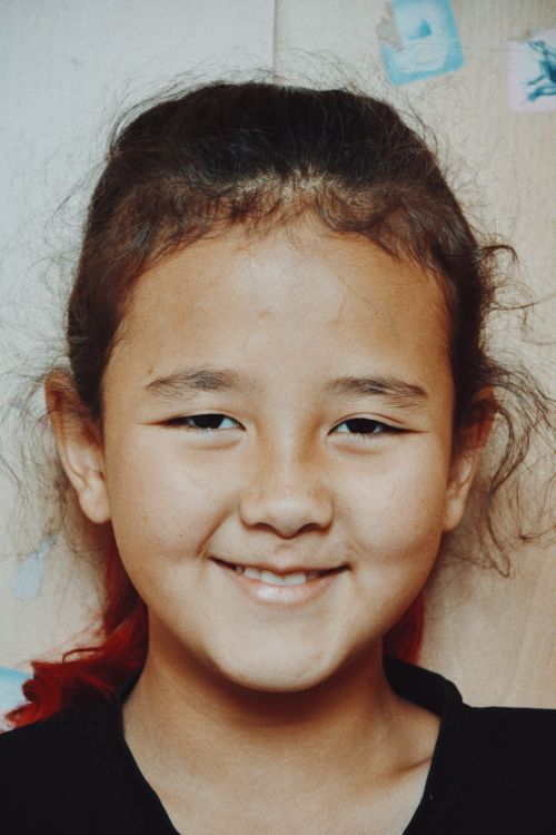 Free Portrait of a smiling Asian girl against a wooden wall, located in Talgar, Kazakhstan. Stock Photo