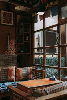 Warm and inviting cafe interior with vintage decor in India, featuring colorful pillows and wooden furniture.