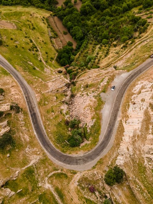 Free Aerial view showcasing a scenic winding road through lush countryside landscape. Stock Photo