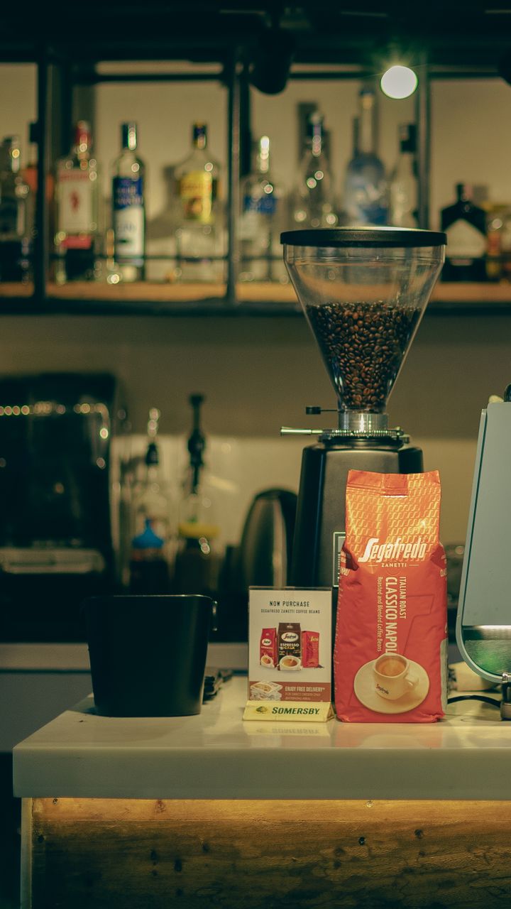wire baker’s rack holding a coffee maker, mugs, and bags of coffee beans