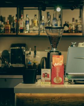 A coffee shop counter displaying an espresso machine, coffee grinder, and various products.