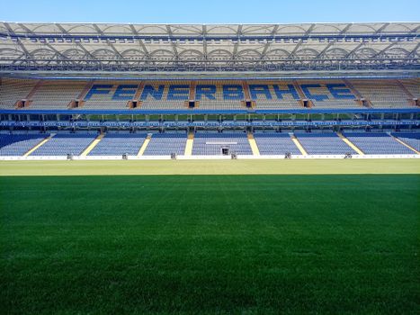 Empty Şükrü Saracoğlu Stadium with green pitch in Istanbul, Türkiye, under clear blue sky.