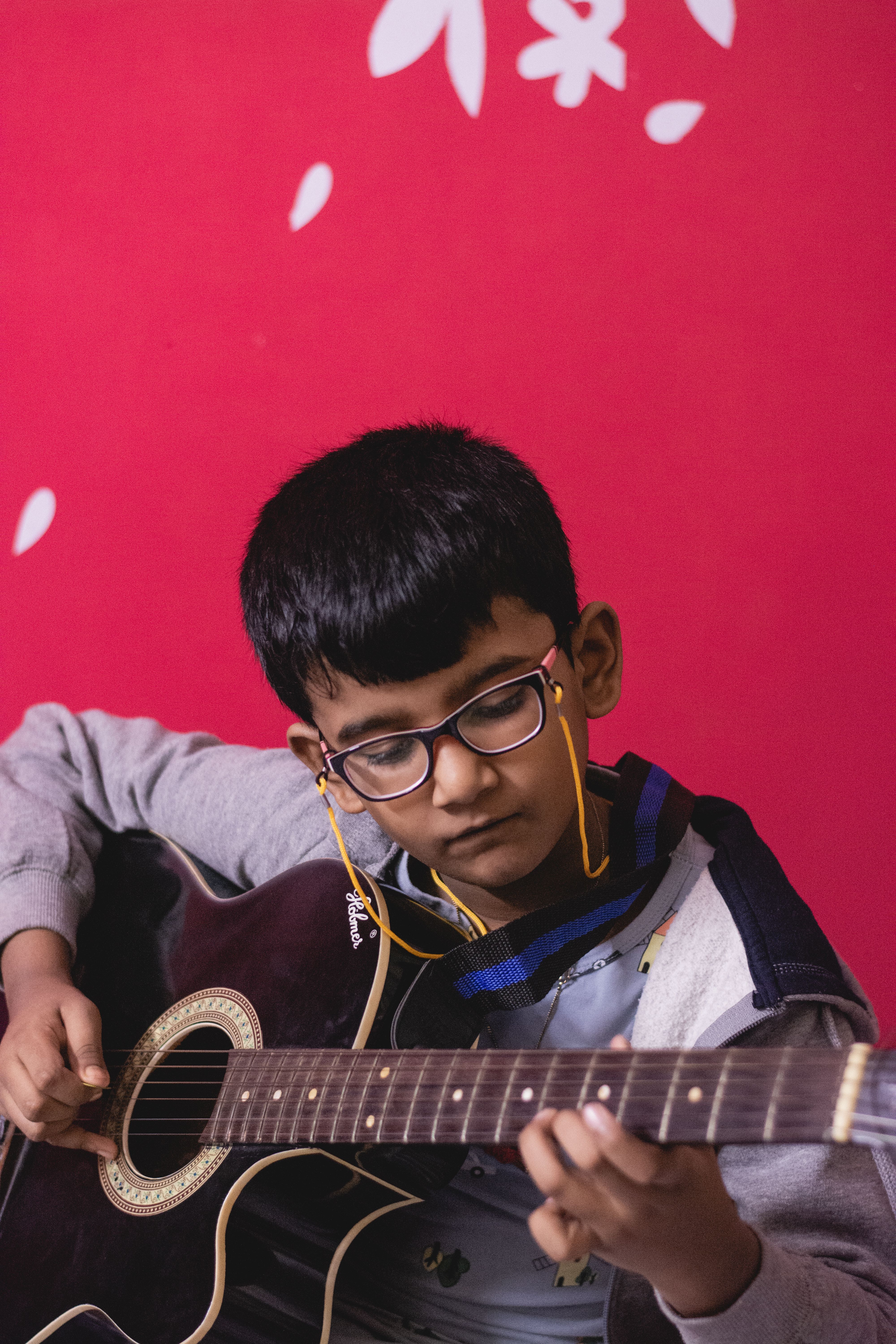 A young child skillfully plays an acoustic guitar, showcasing musical talent.
