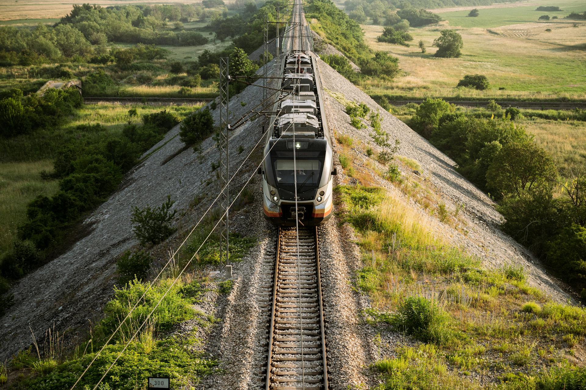 Aerial view of a train on railway tracks crossing the rural countryside of Montenegro in summer.