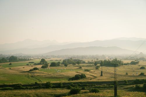 Free Peaceful rural scenery with misty fields and distant mountains at dawn. Stock Photo