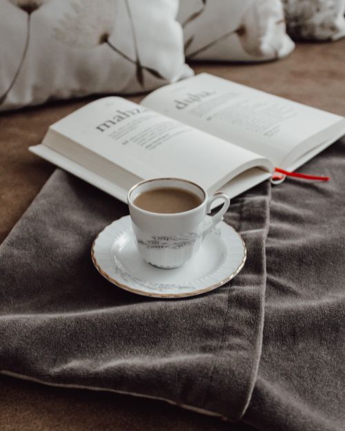 Free Warm and cozy setup with a cup of coffee and an open book on a soft blanket. Stock Photo