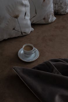 A comforting scene of coffee on a bed with floral cushions, perfect for relaxation.
