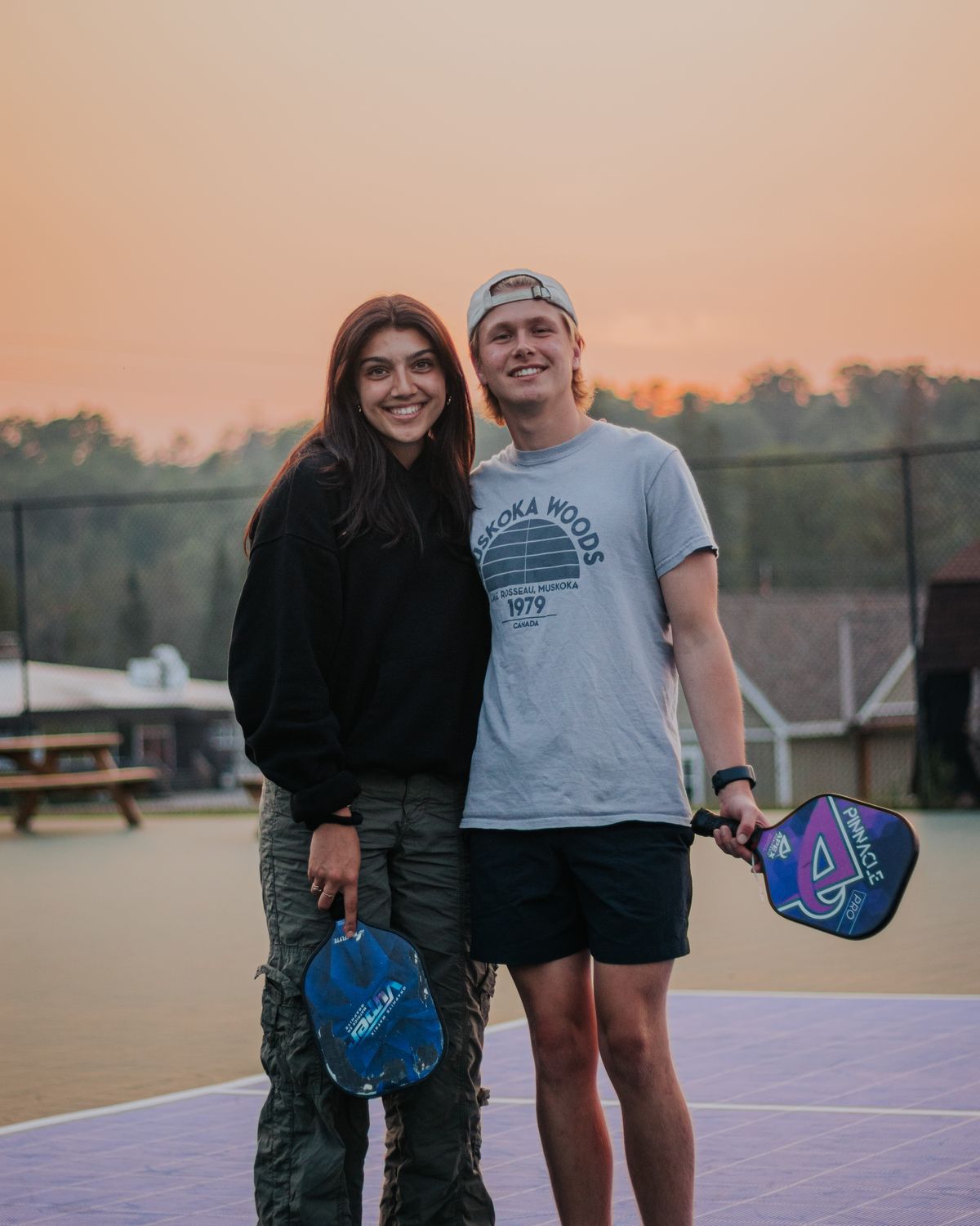 Couple having fun playing pickleball at sunset
