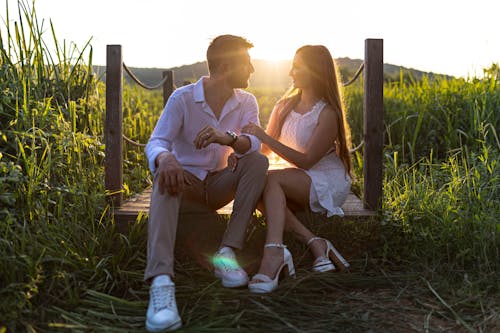 Woman in White Dress and Man in White Shirt Sitting Together at Sunset