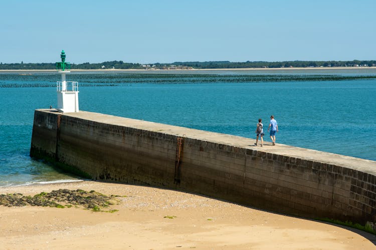 View Of People Walking Toward The Mesquer Lighthouse, Pointe De Merquel, Loire-Atlantique, France