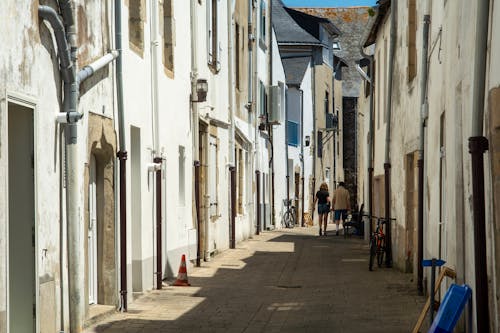 Back View of Pedestrians Walking in a Narrow Alley between Buildings in a Town 