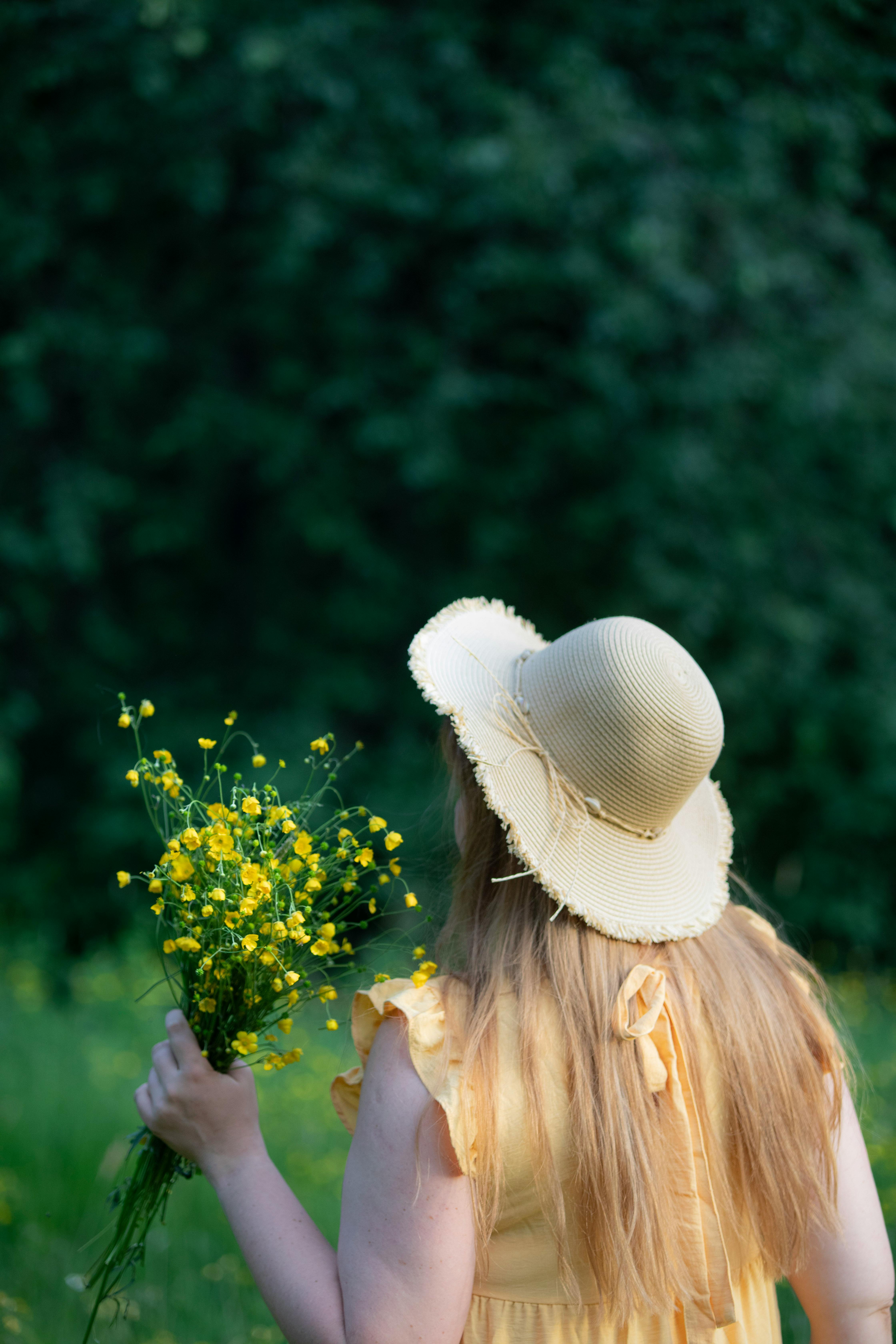 woman in hat holding bundle of flowers