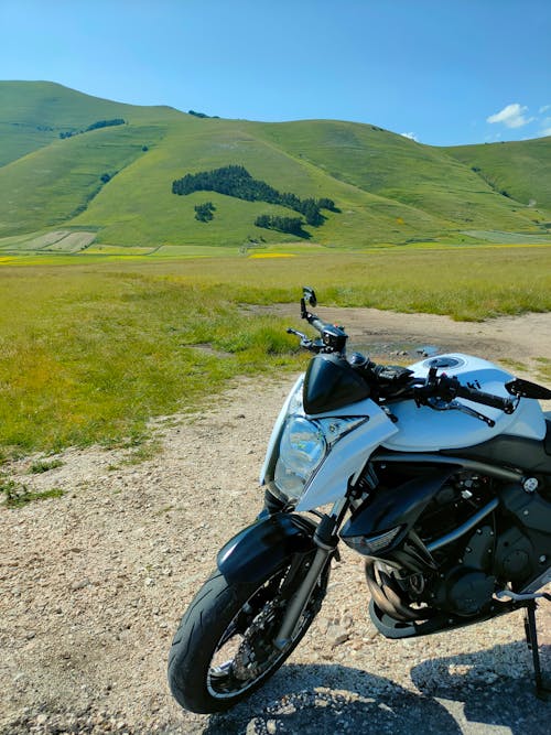 Motorcycle on a Dirt Road Among Green Hills