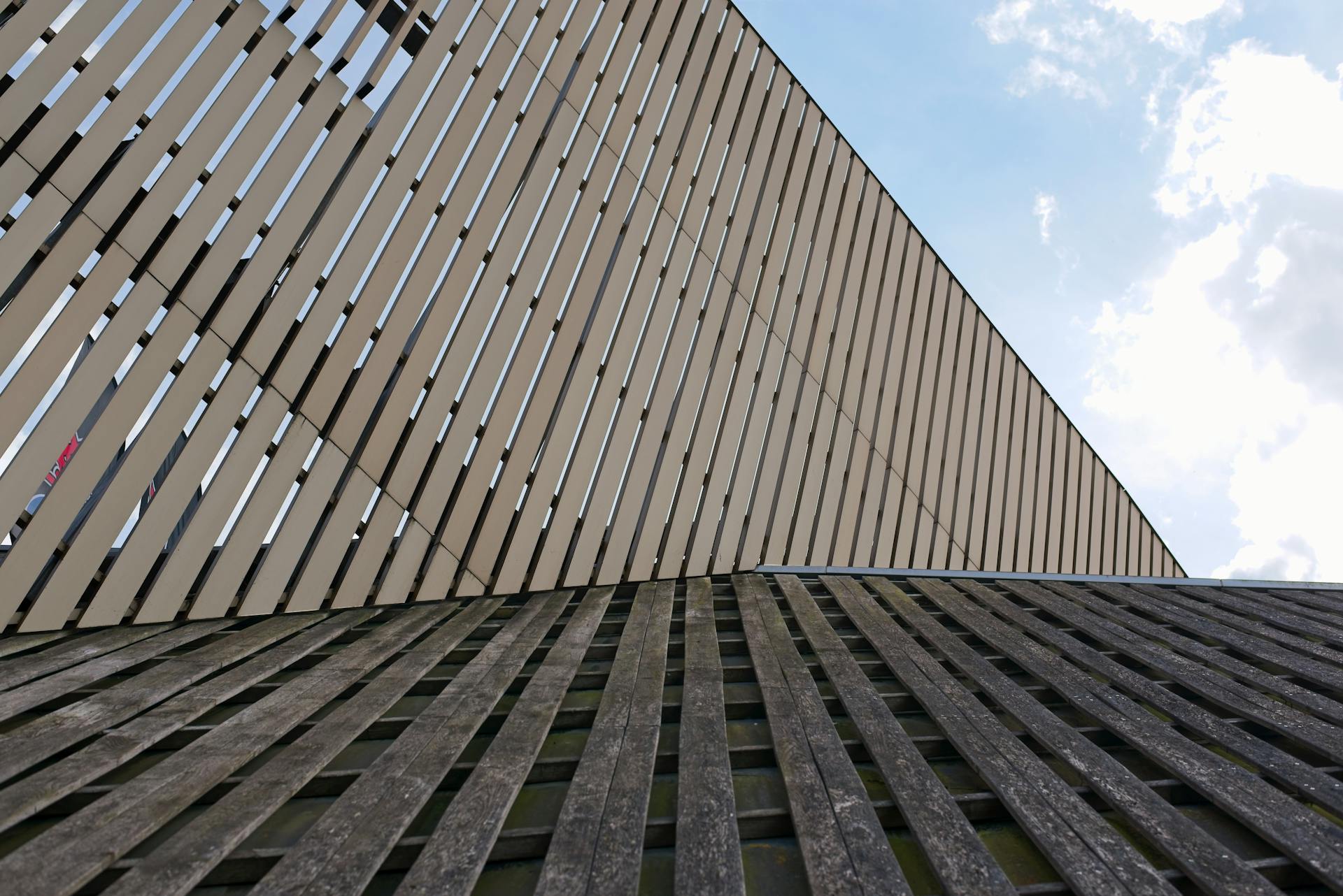 Contemporary building exterior featuring vertical wooden panels against a bright sky.