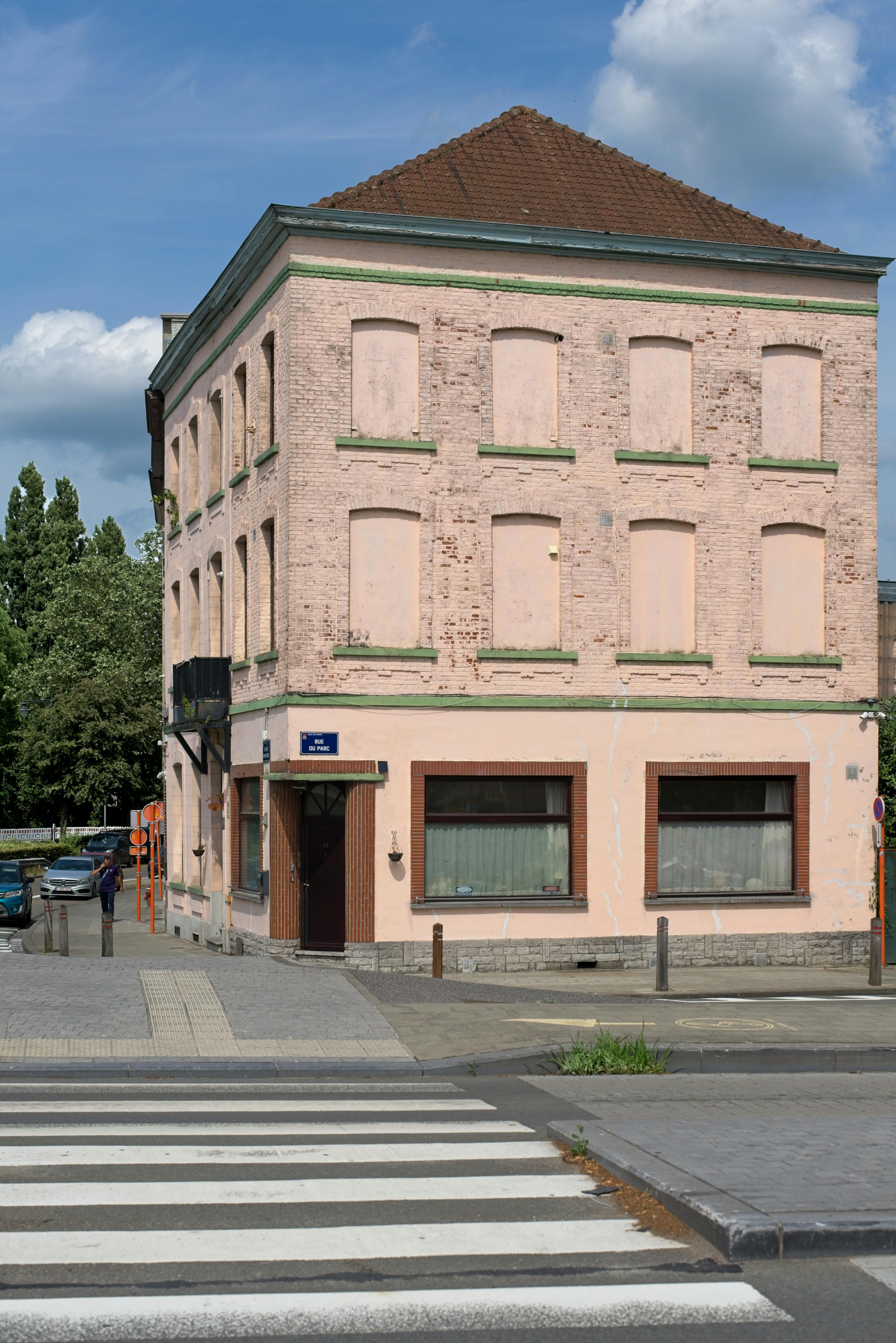 Free Three-story building with bricked windows on an urban street corner featuring a crosswalk. Stock Photo