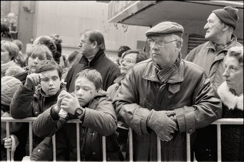 An Old Photograph of People Standing by the Barriers on the Street