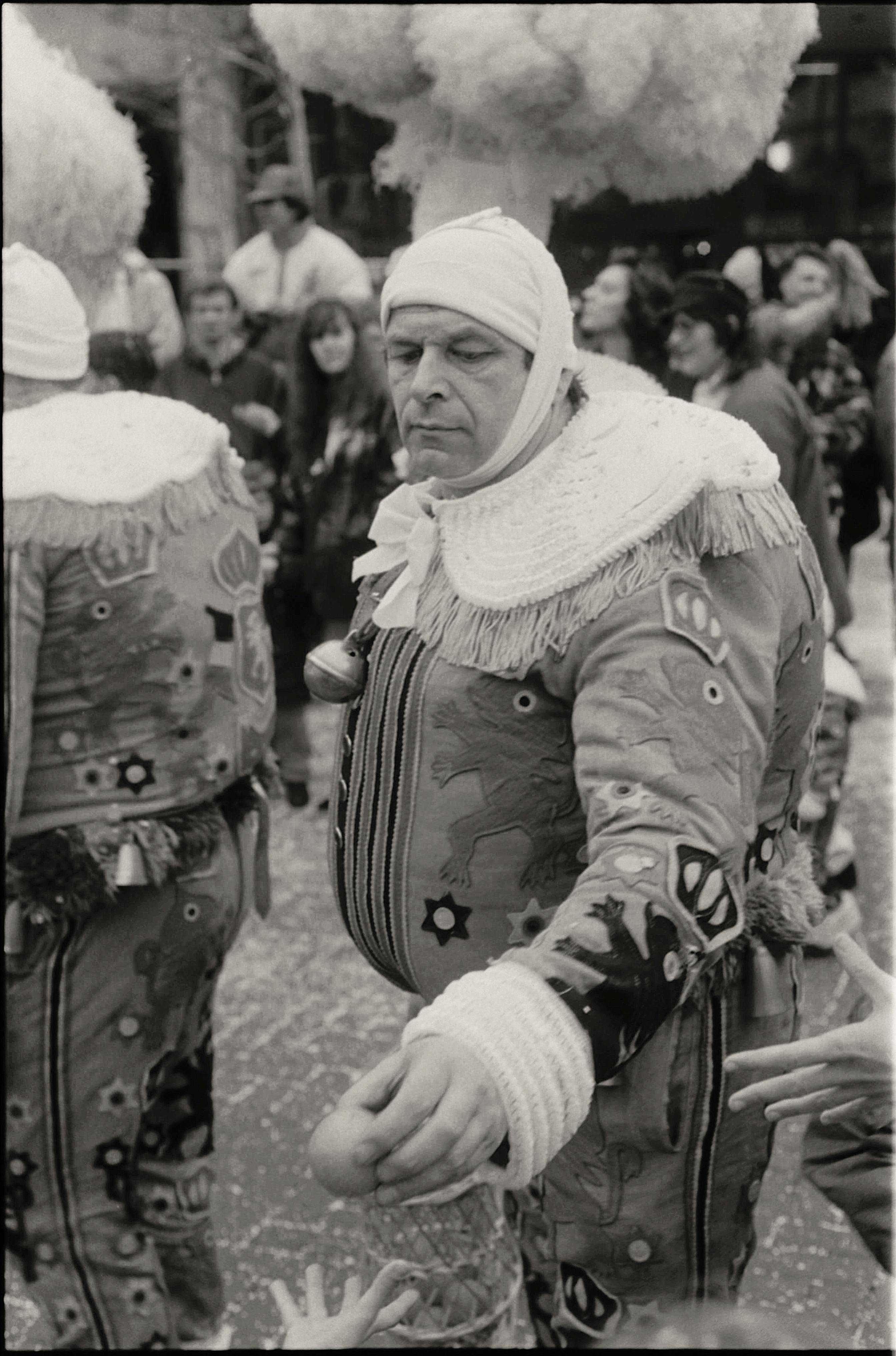 A black and white photo of a city parade featuring people in vintage costumes.