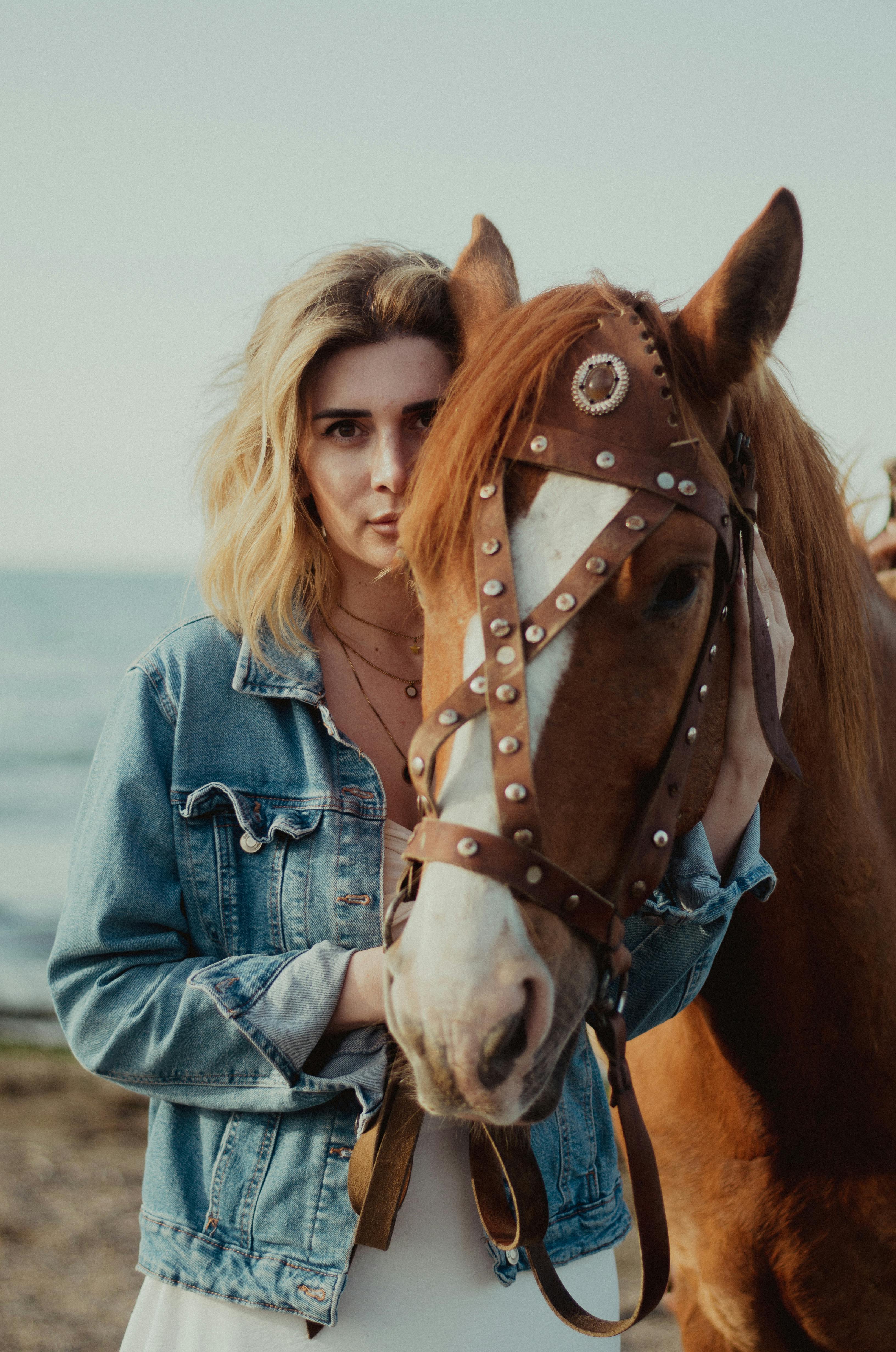 Artistic portrait of a woman in a jean jacket with a horse by the seaside in Baku.