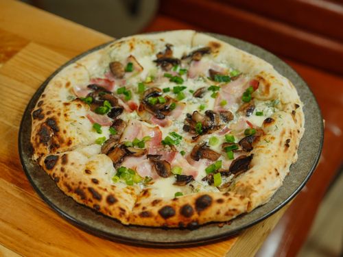 Free A delicious wood-fired pizza topped with mushrooms, ham, and fresh spring onions. Stock Photo