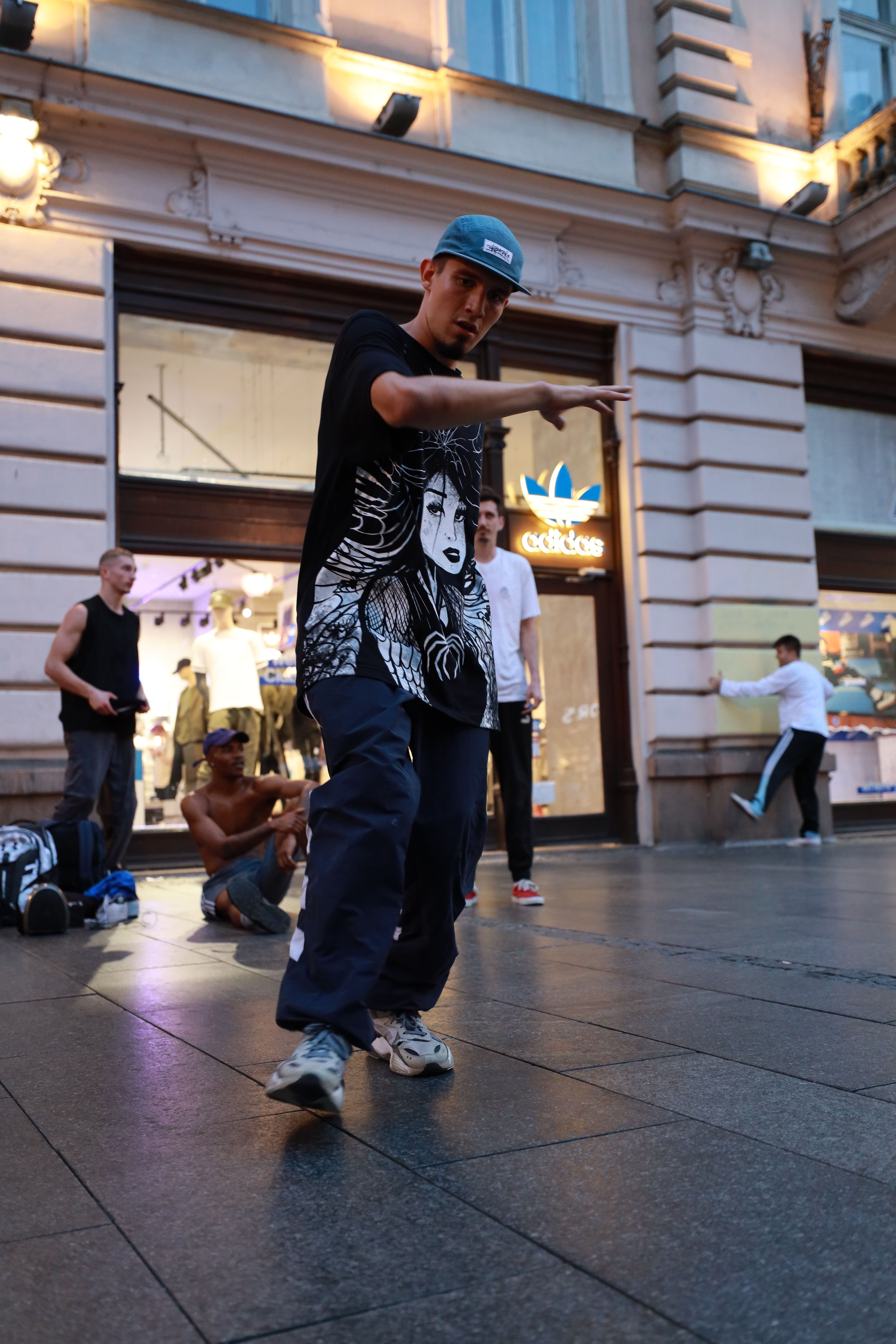 A street dancer performs energetically in an urban environment as people look on.