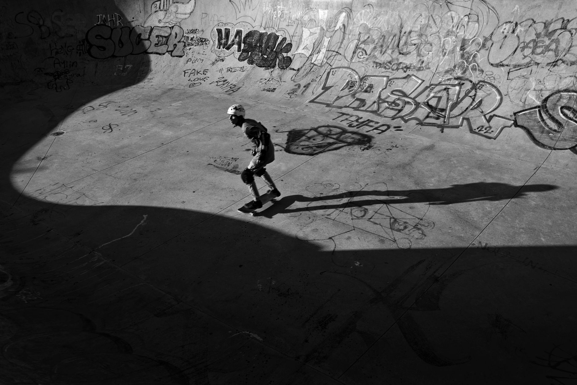 Houston skatepark concrete bowl under afternoon sunlight, empty coping and faded punk stickers on nearby walls