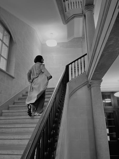 Back View of a Woman in a Coat Walking Up the Stairs 