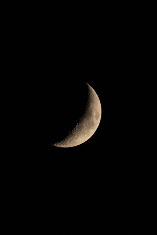 Free A serene crescent moon glowing in the dark night sky with craters visible. Stock Photo