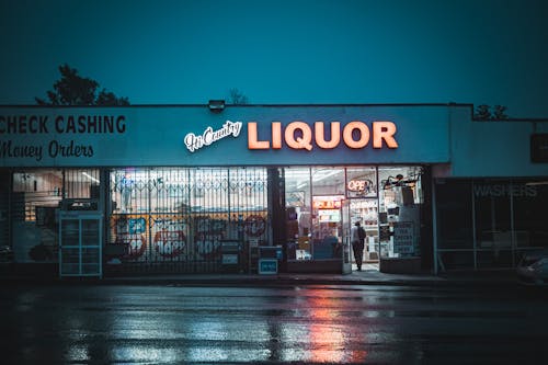 Illuminated Sign of a Liquor Store Reflecting in Wet Asphalt after Rain 