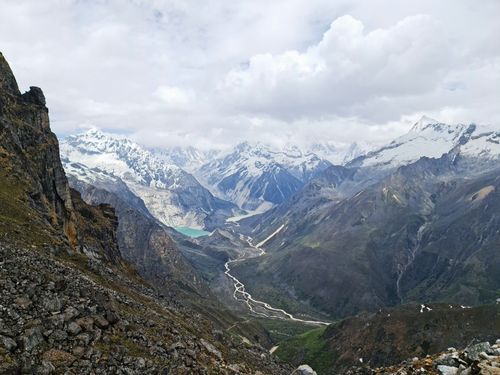 Free Stunning aerial view of a rugged mountain range with snow-capped peaks and winding river below. Stock Photo