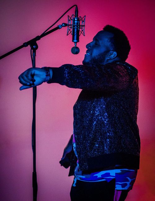 Free Dynamic portrait of a male singer energetically performing in a studio with a red background. Stock Photo
