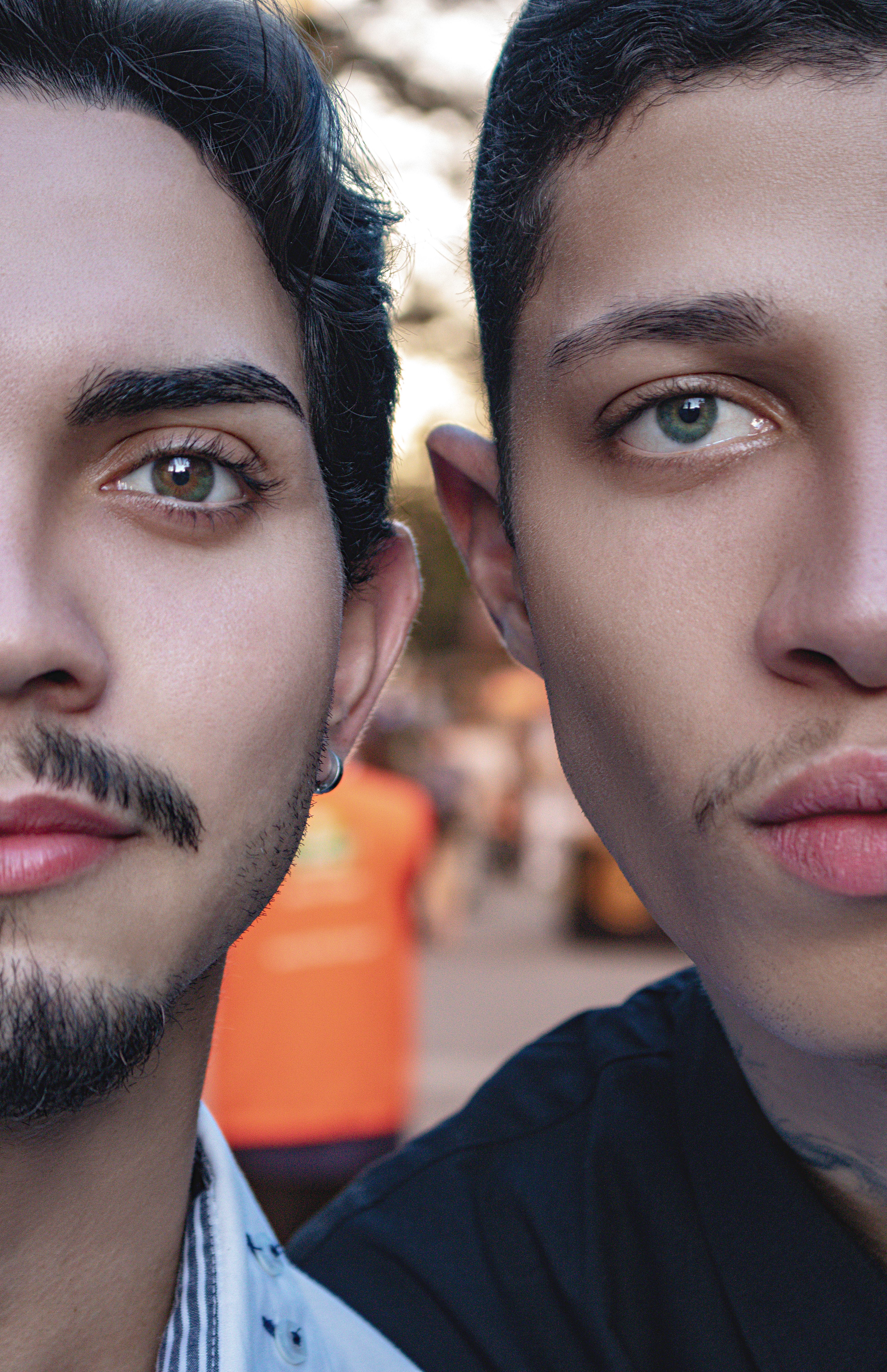 Close-up of two young men with expressive eyes and facial hair in São Paulo, Brazil.