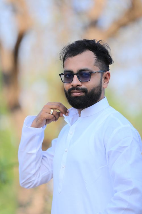Free Portrait of a confident Indian man in a white kurta adjusting his collar outdoors. Stock Photo