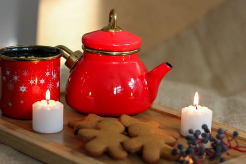Free Warm winter setup with a red teapot, gingerbread cookies, and candles on a wooden tray, ideal for Christmas vibes. Stock Photo