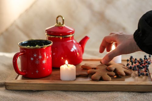 Hand over Cookies on Tray with Wax Candle and Decorated Cup