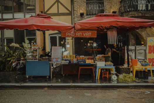 Vibrant outdoor street market featuring local vendors selling fresh produce and goods under red canopies.