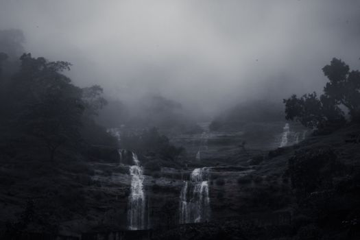 Mysterious waterfall shrouded in mist, creating a moody and serene landscape.